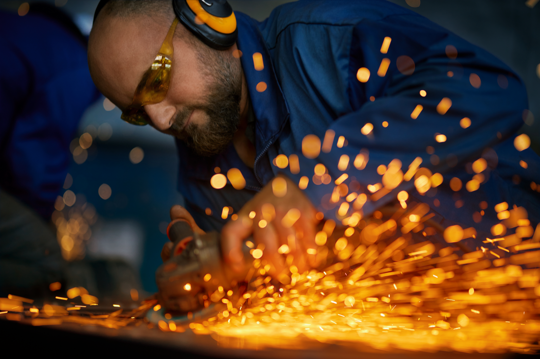 Worker operating electric steel cutter with sparks
